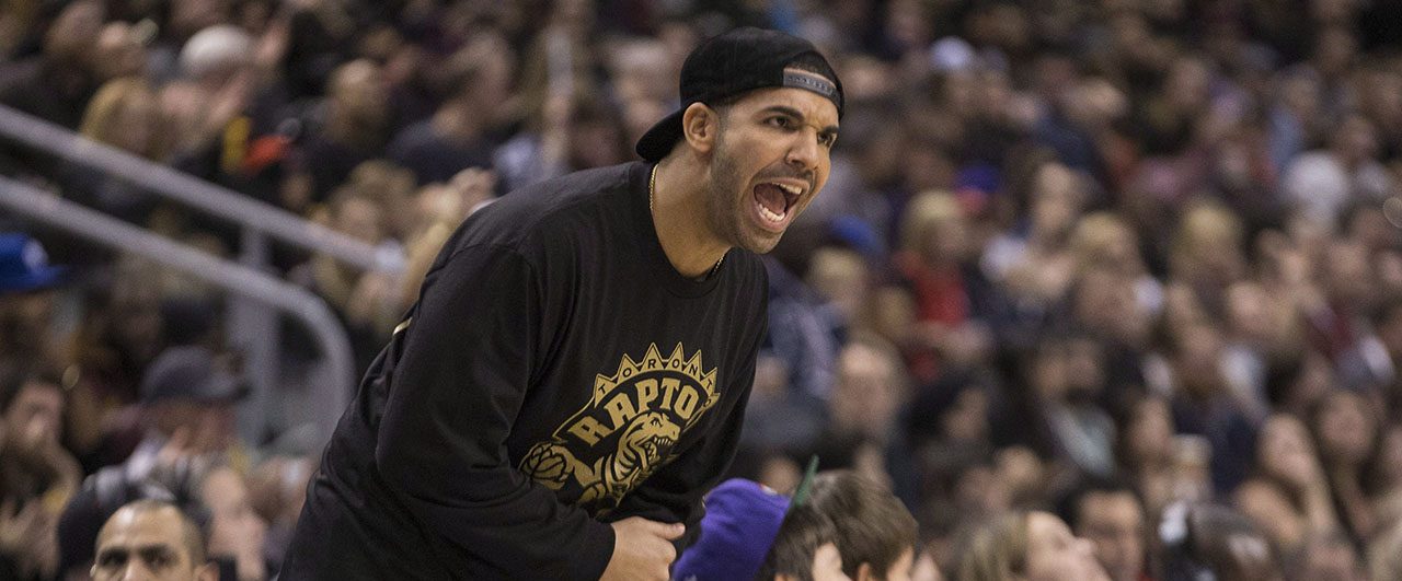 Drake au bord du terrain, avec un pull des Raptors.