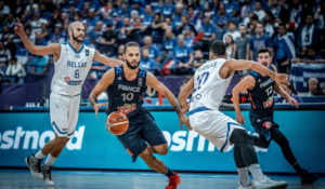 Evan Fournier devant deux joueurs Grecs, sous le maillot de l'équipe de France