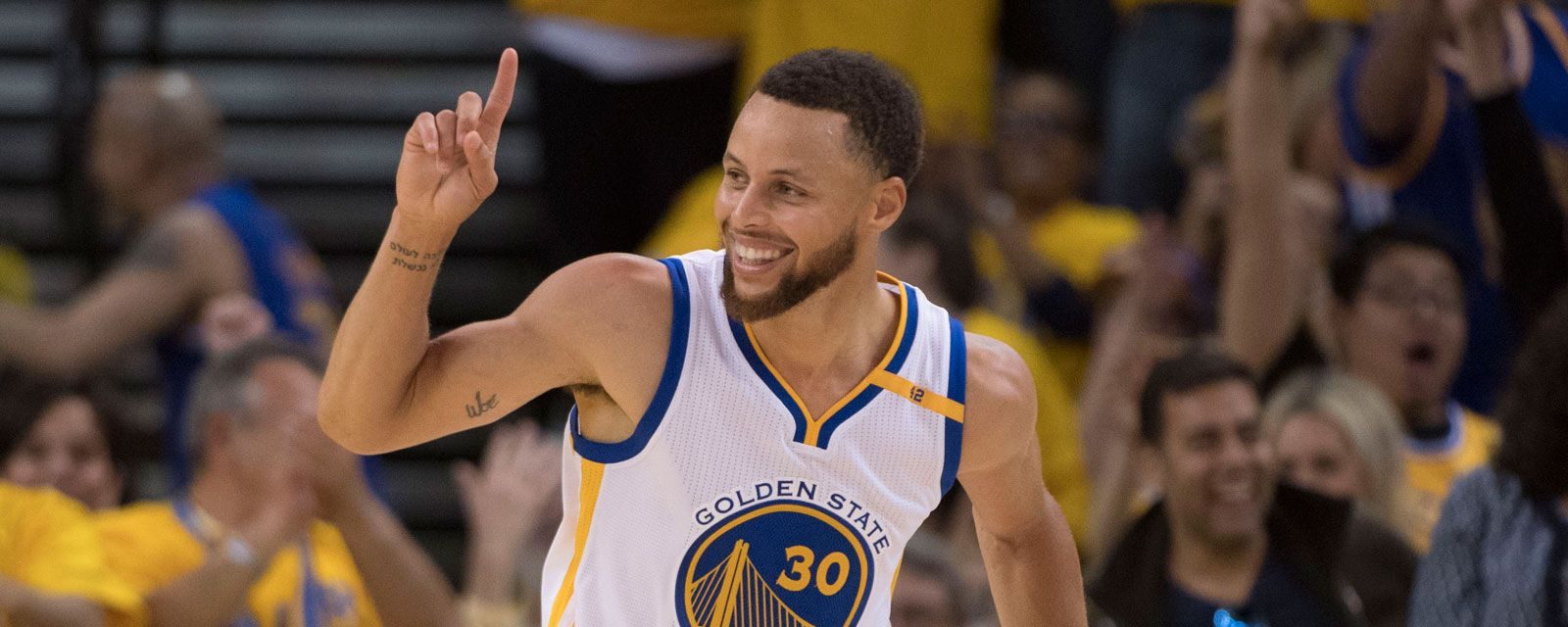 Stephen Curry, doigt levé, sous le maillot des Warriors.