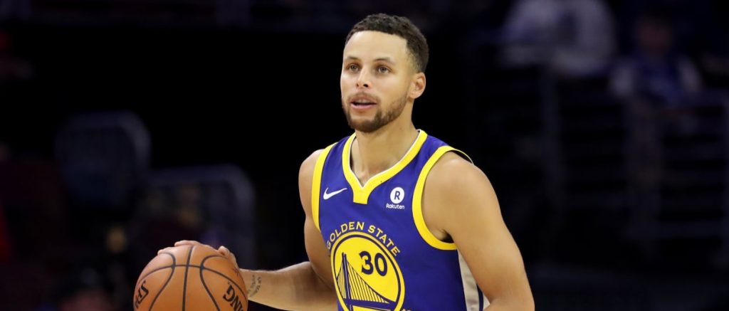 Stephen Curry, balle en main, sous le maillot des Warriors.