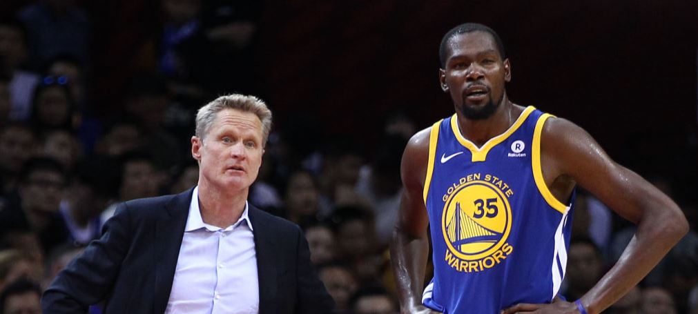 Steve Kerr discute avec Kevin Durant depuis le banc