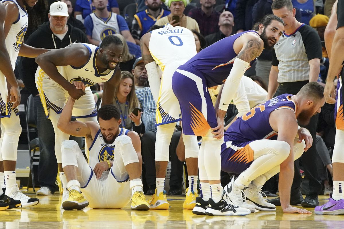 Stephen Curry blessé, relevé par Draymond Green, lors du match face aux Suns