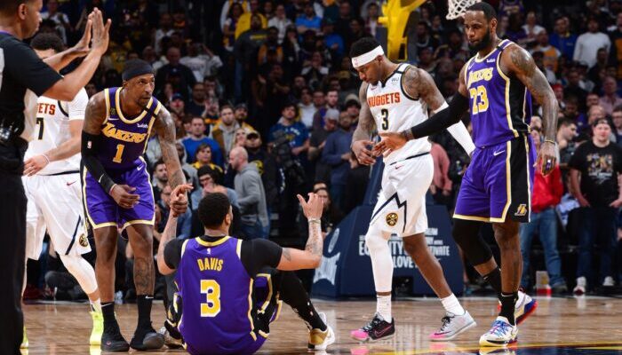 Les joueurs des Lakers Kentavious Caldwell-Pope et Lebron James relèvent leur coéquipier, Anthony Davis, lors du match opposant les Los Angeles Lakers aux Denver Nuggets, le 12 février 2020