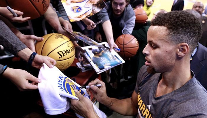 Stephen Curry dédicaçant un t-shirt après un échauffement des Golden State Warriors