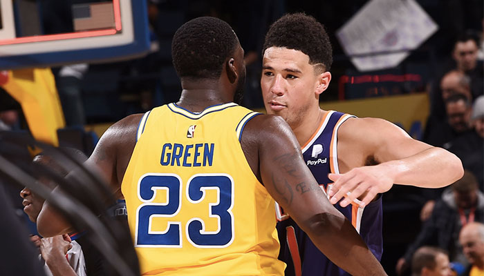 Les stars NBA Devin Booker et Draymond Green s’enlacent après un match entre les Golden State Warriors et les Phoenix Suns