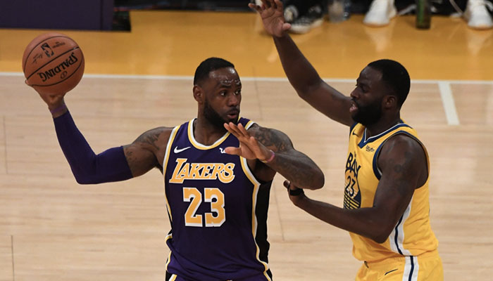 La superstar NBA des Los Angeles Lakers LeBron James, ballon en main, face à l’intérieur des Golden State Warriors Draymond Green