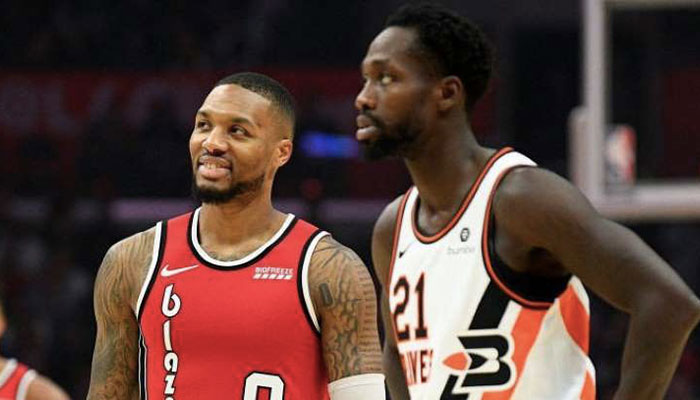 La superstar NBA Damian Lillard sourire aux lèvres devant Patrick Beverley lors d’un match entre les Portland Trail Blazers et les Los Angeles Clippers