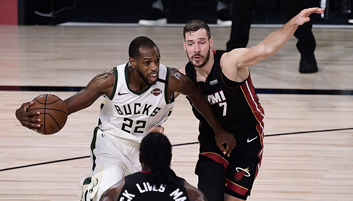 Le joueur des Milwaukee Bucks Khris Middleton, balle en main, attaque la défense du Miami Heat et Goran Dragic devant les yeux de Jae Crowder