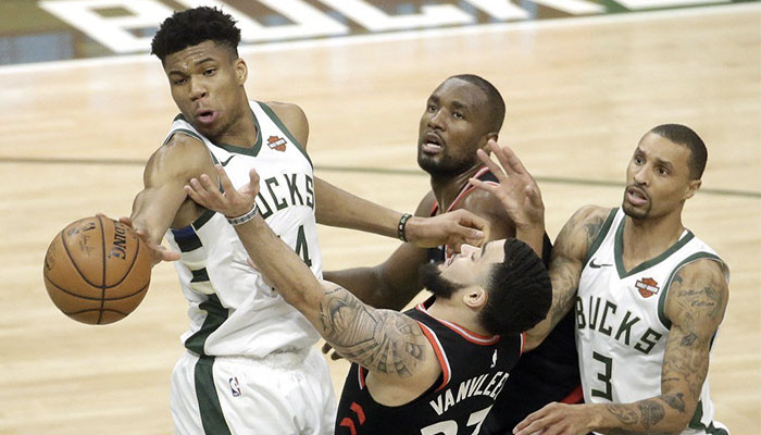 La superstar NBA Giannis Antetokounmpo, ballon en main, devant les yeux de Fred VanVleet, Serge Ibaka et George Hill lors d’un match entre les Milwaukee Bucks et les Toronto Raptors