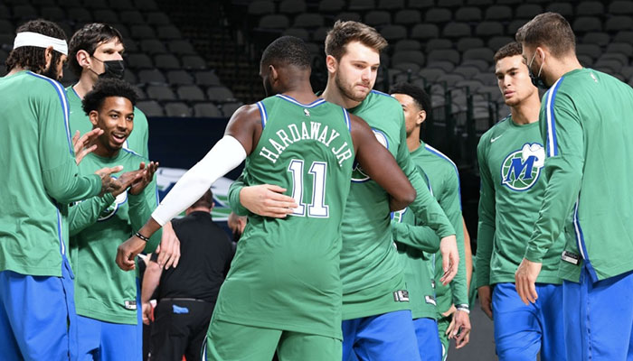 La star slovène des Dallas Mavericks, Luka Doncic, enlace son coéquipier Tim Hardaway Jr. au milieu du reste de l'effectif